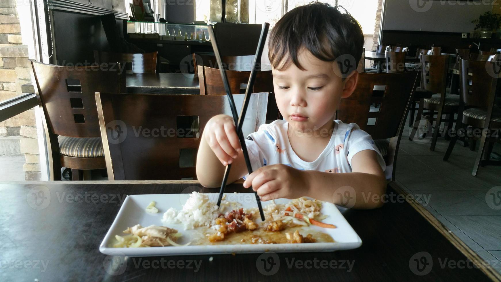 lindo joven chino y caucásico aprendiendo a usar palillos en el restaurante foto