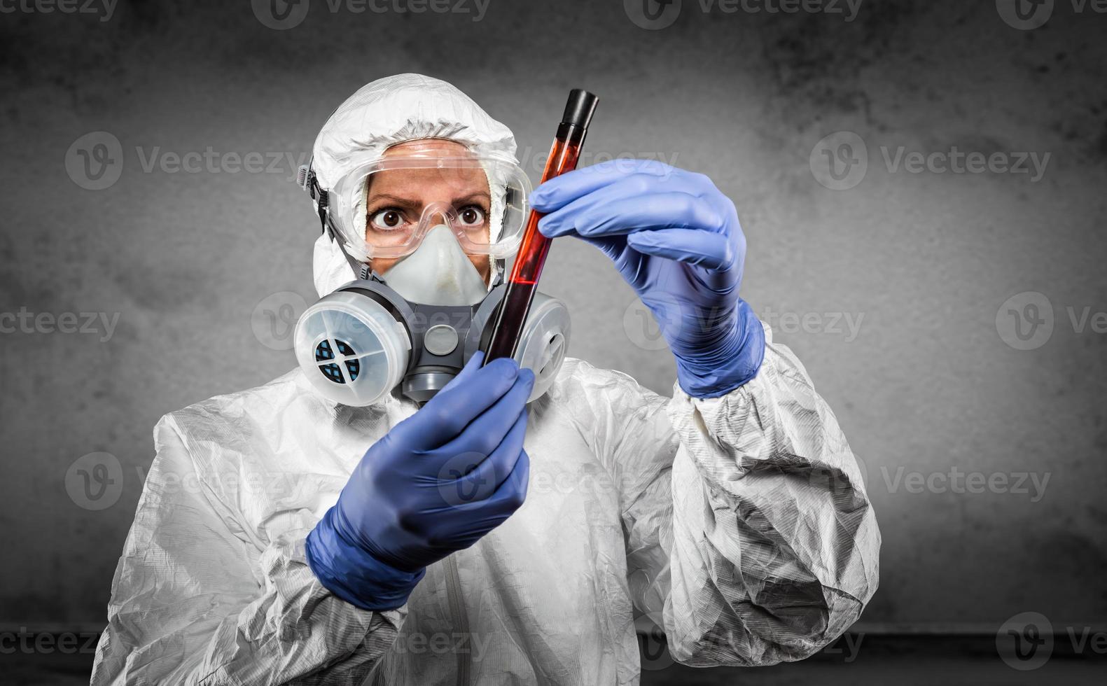 mujer con traje hazmat y máscara de gas sosteniendo un tubo de ensayo de sangre foto