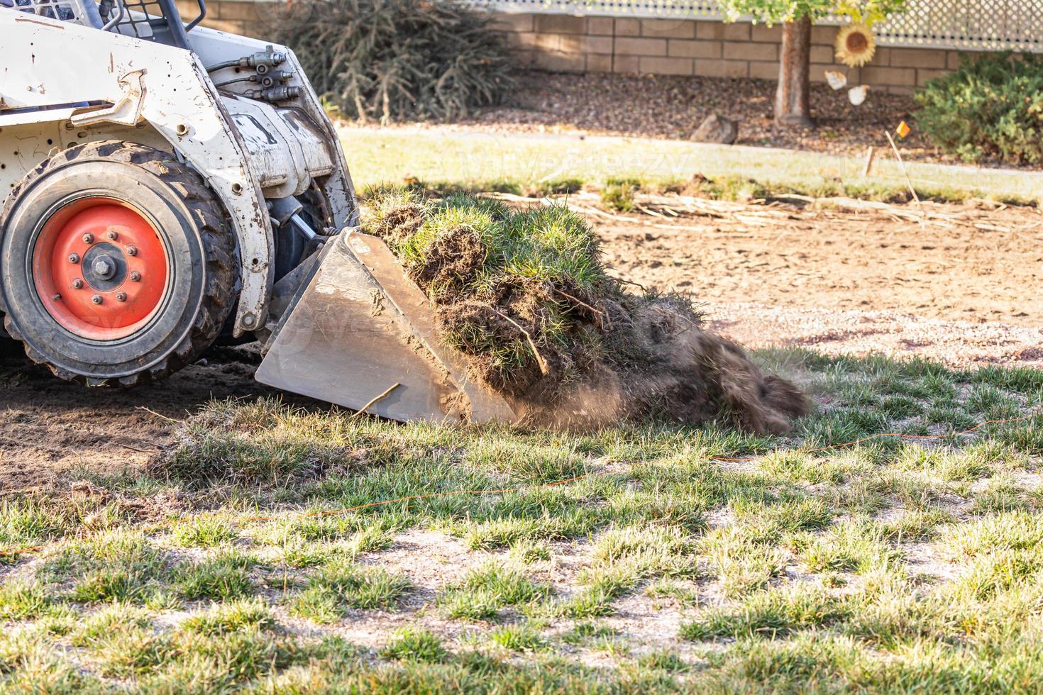 Small Bulldozer Removing Grass From Yard Preparing For Pool Installation photo