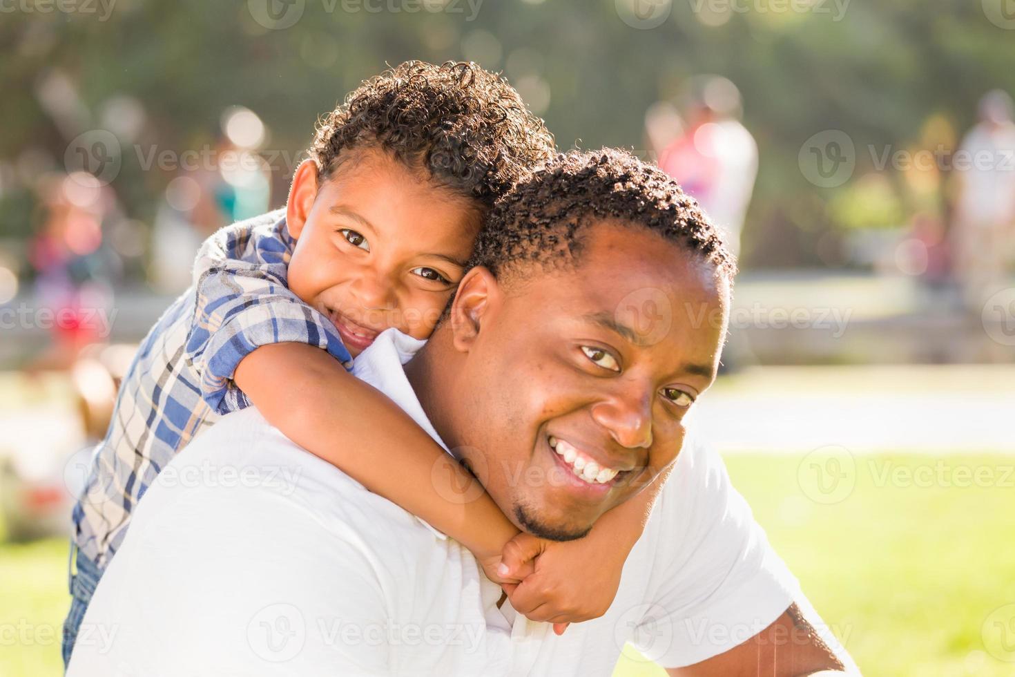 feliz padre afroamericano e hijo de raza mixta jugando en el parque foto