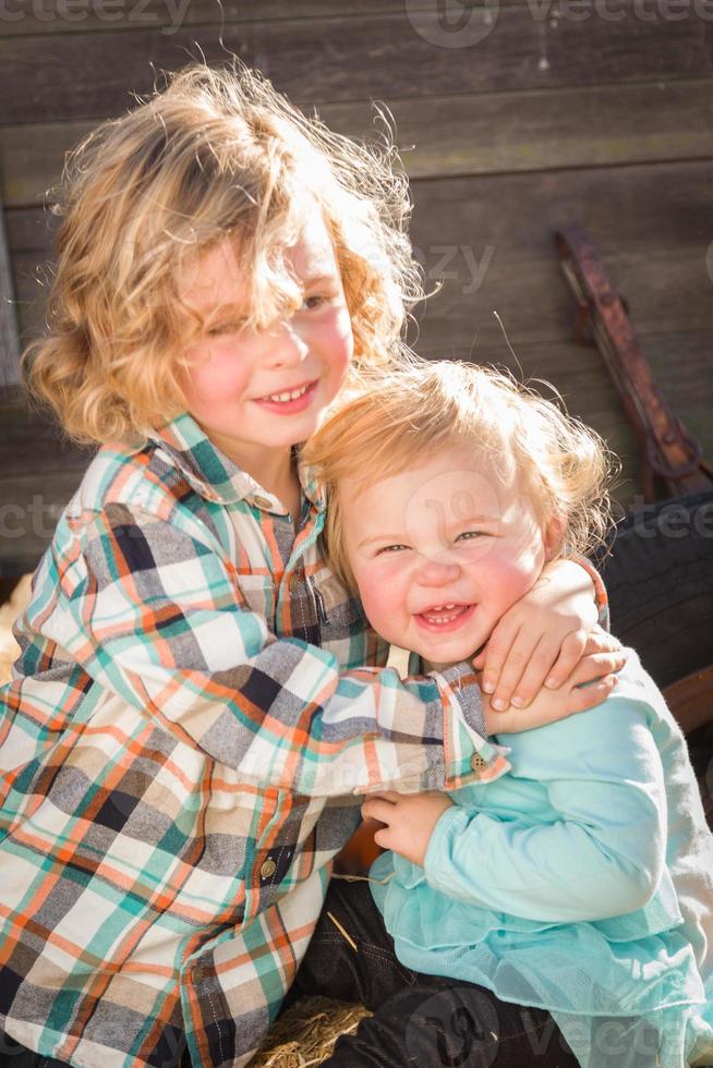 un dulce niño juega con su hermanita en un rancho rústico en el huerto de calabazas. foto