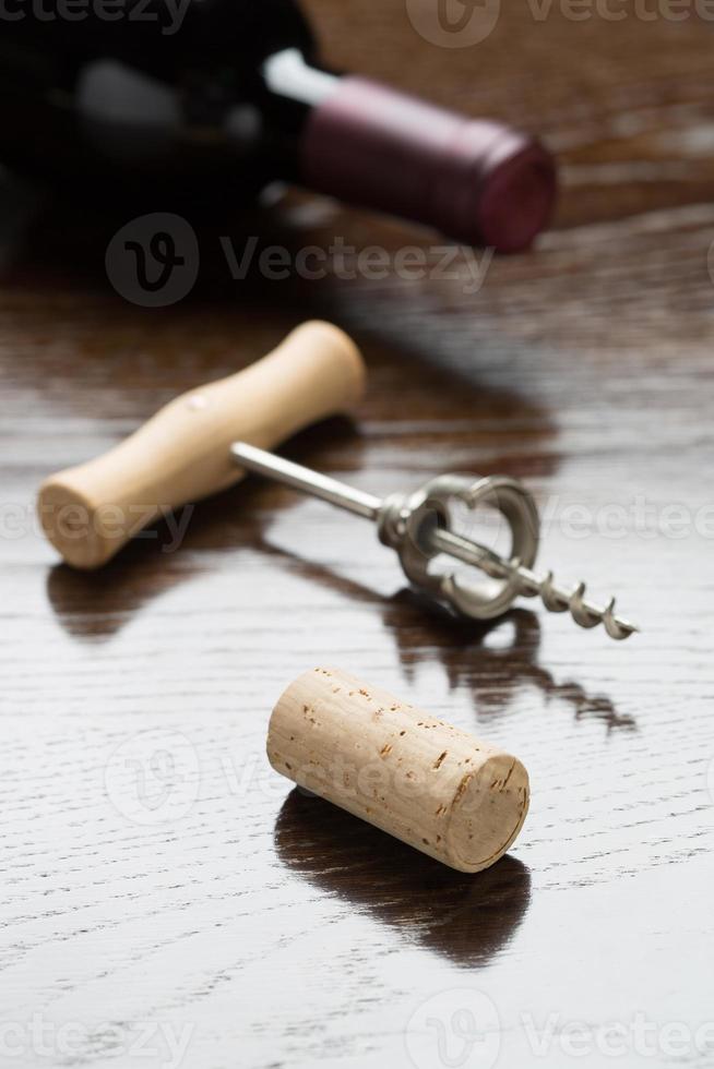 Abstract Wine Bottle, Cork and Corkscrew Laying on a Reflective Wood Surface. photo