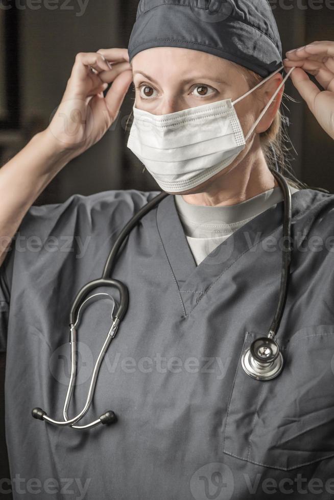 Female Doctor or Nurse with Stethoscope Putting On Protective Face Mask photo