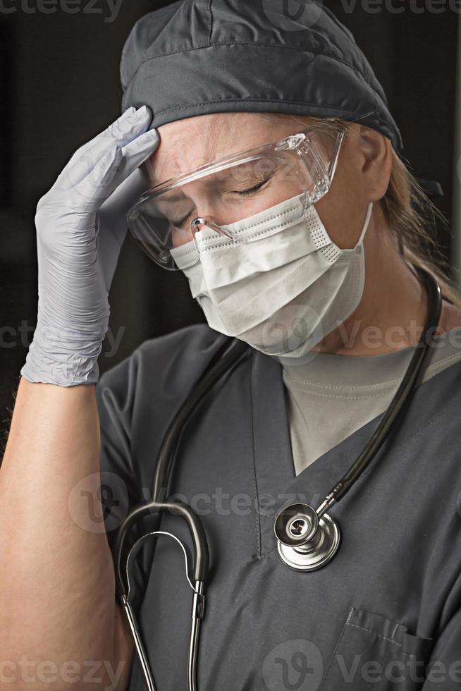 Female Doctor or Nurse Wearing Scrubs, Protective Face Mask and Goggles photo