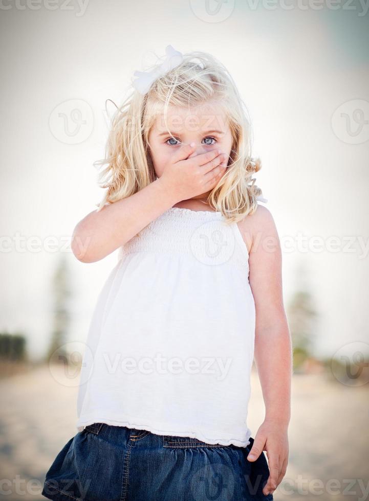 Adorable Blue Eyed Girl Covering Her Mouth photo