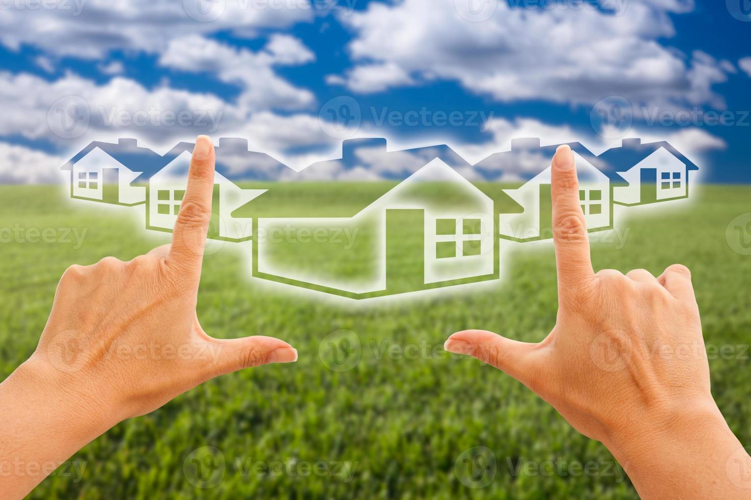Female Hands Framing Houses Over Grass and Sky photo