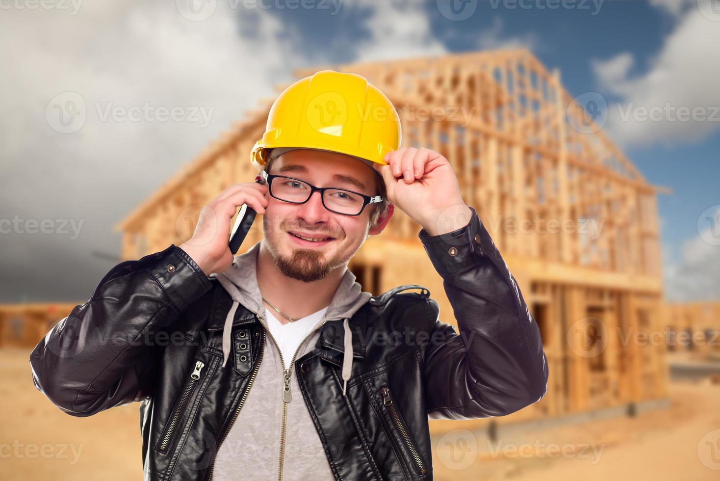 Young Cunstruction Worker on Cell Phone In Front of House photo