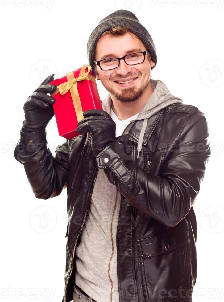 Warmly Dressed Young Man Holding Wrapped Gift To His Ear photo