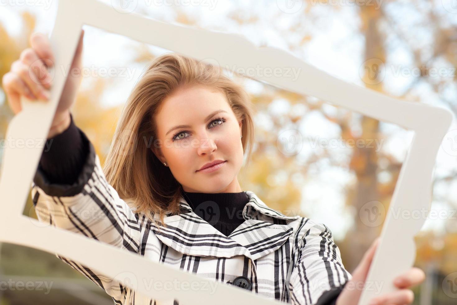 bastante, mujer joven, sonriente, en el parque, con, marco de imagen foto