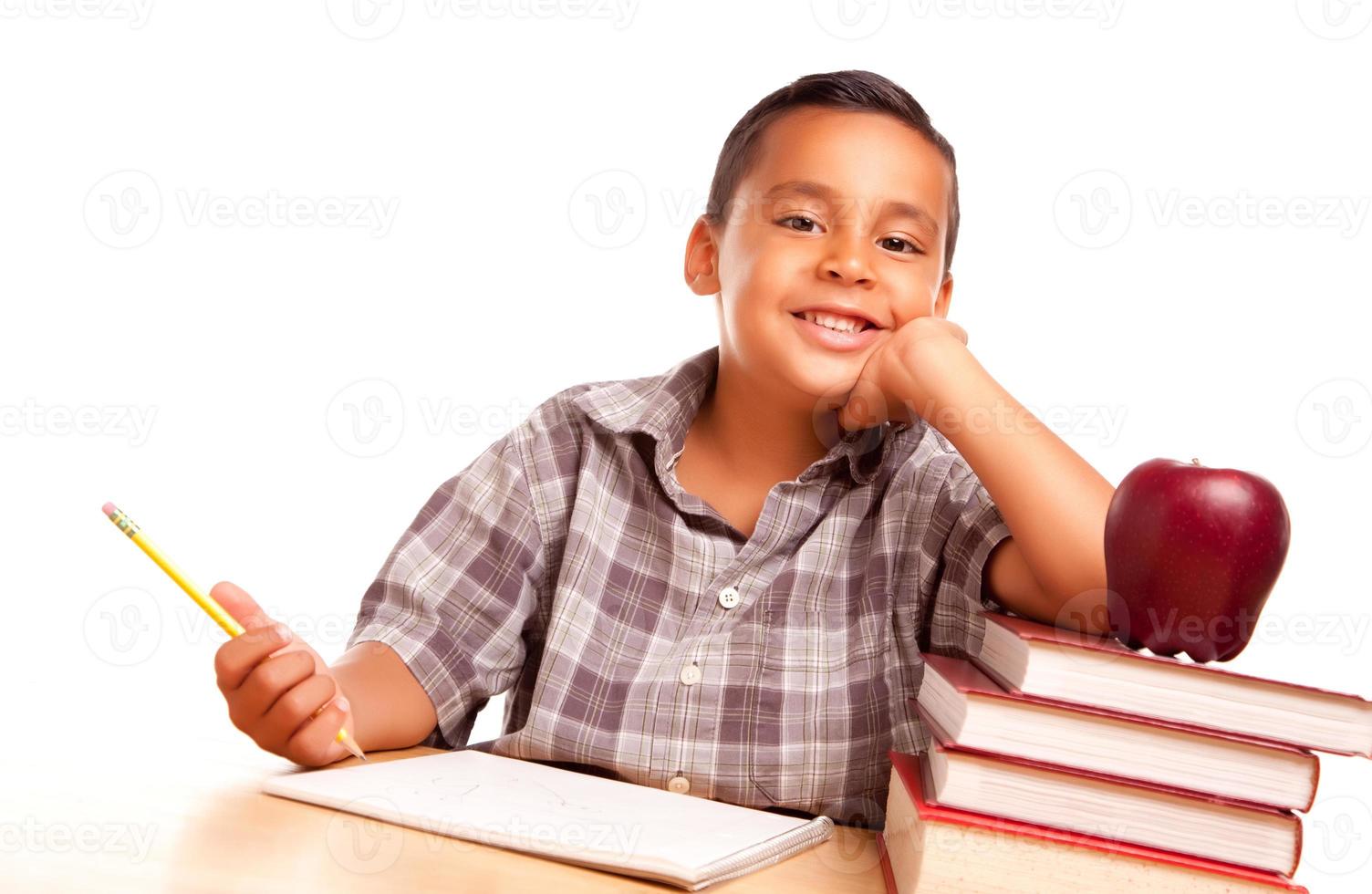 adorable niño hispano con libros, manzana, lápiz y papel foto