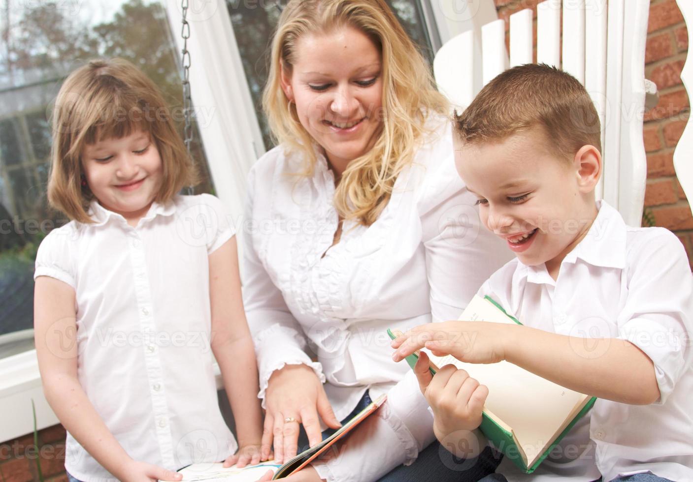 Young Boy Reads to His Mother and Sister photo