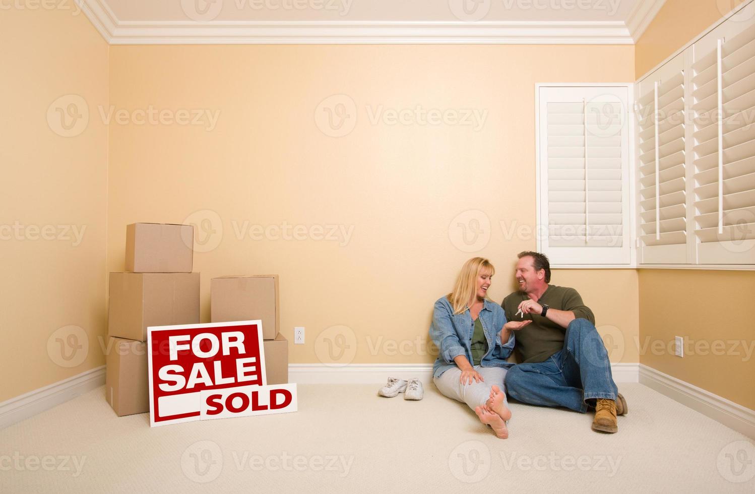 Couple on Floor Near Boxes and Sold Real Estate Signs photo