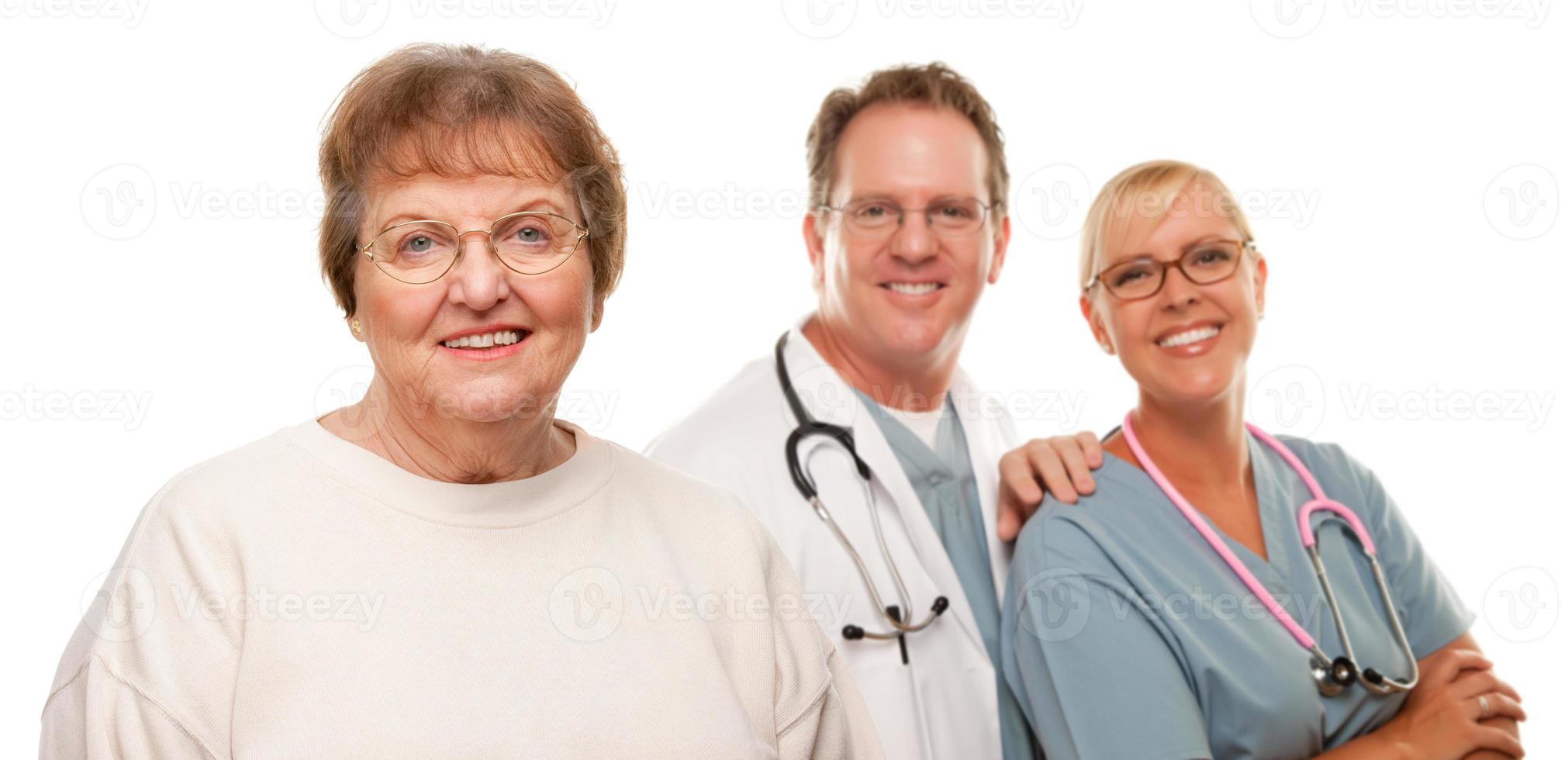 mujer mayor sonriente con médico y enfermera detrás foto