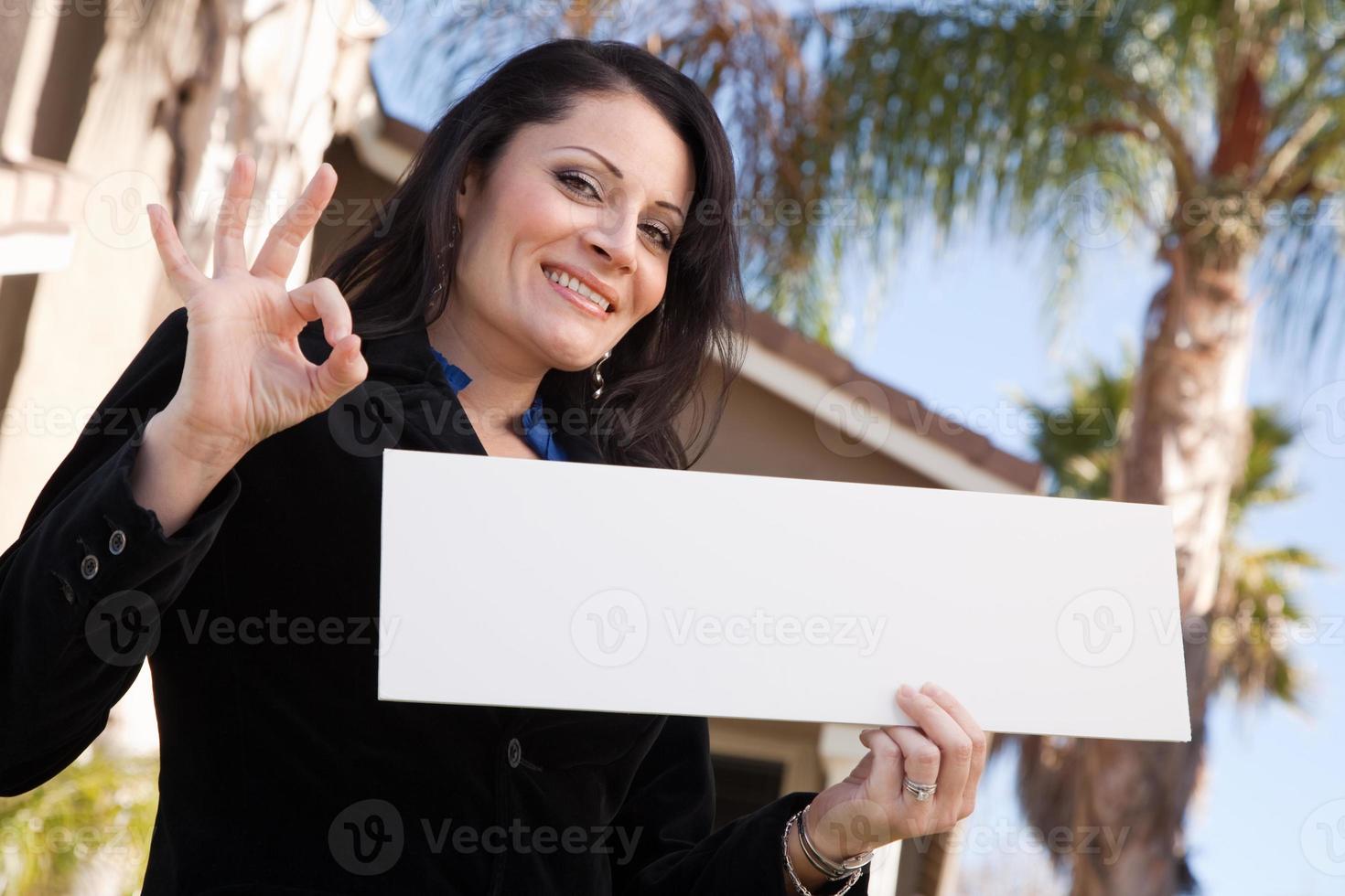 Attractive Hispanic Woman Holding Blank Sign in Front of House photo