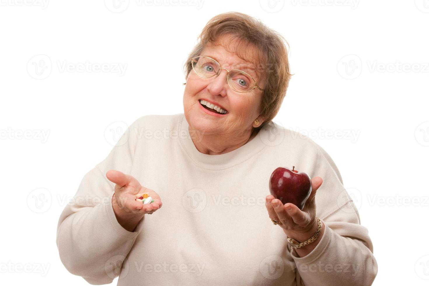 Confused Senior Woman Holding Apple and Vitamins photo
