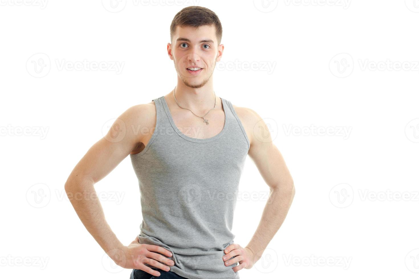 young sporty guy looks into the camera and keeps his hands on the sides photo