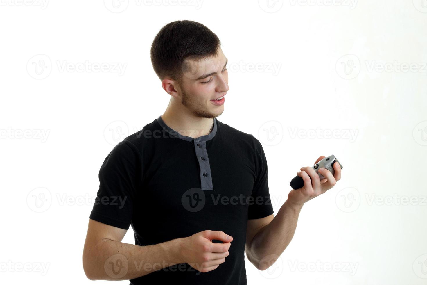 beautiful smiling young man in a black t-shirt holding a Clipper to shave close-up photo