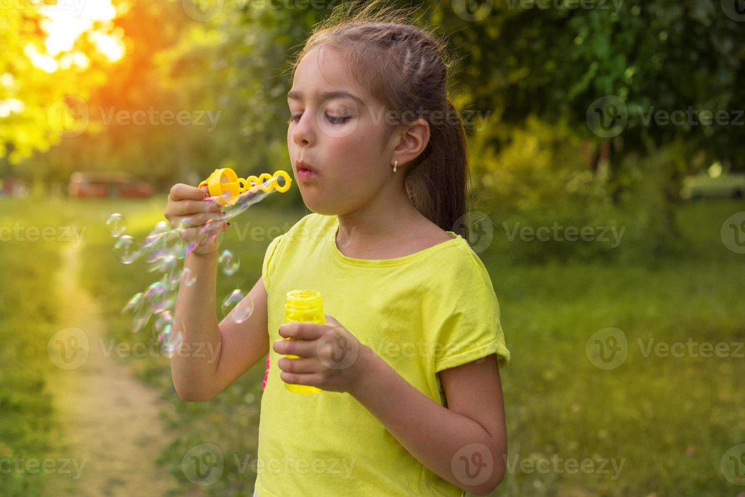 portrait of cute little girl that stands on the street and puts bubbles photo