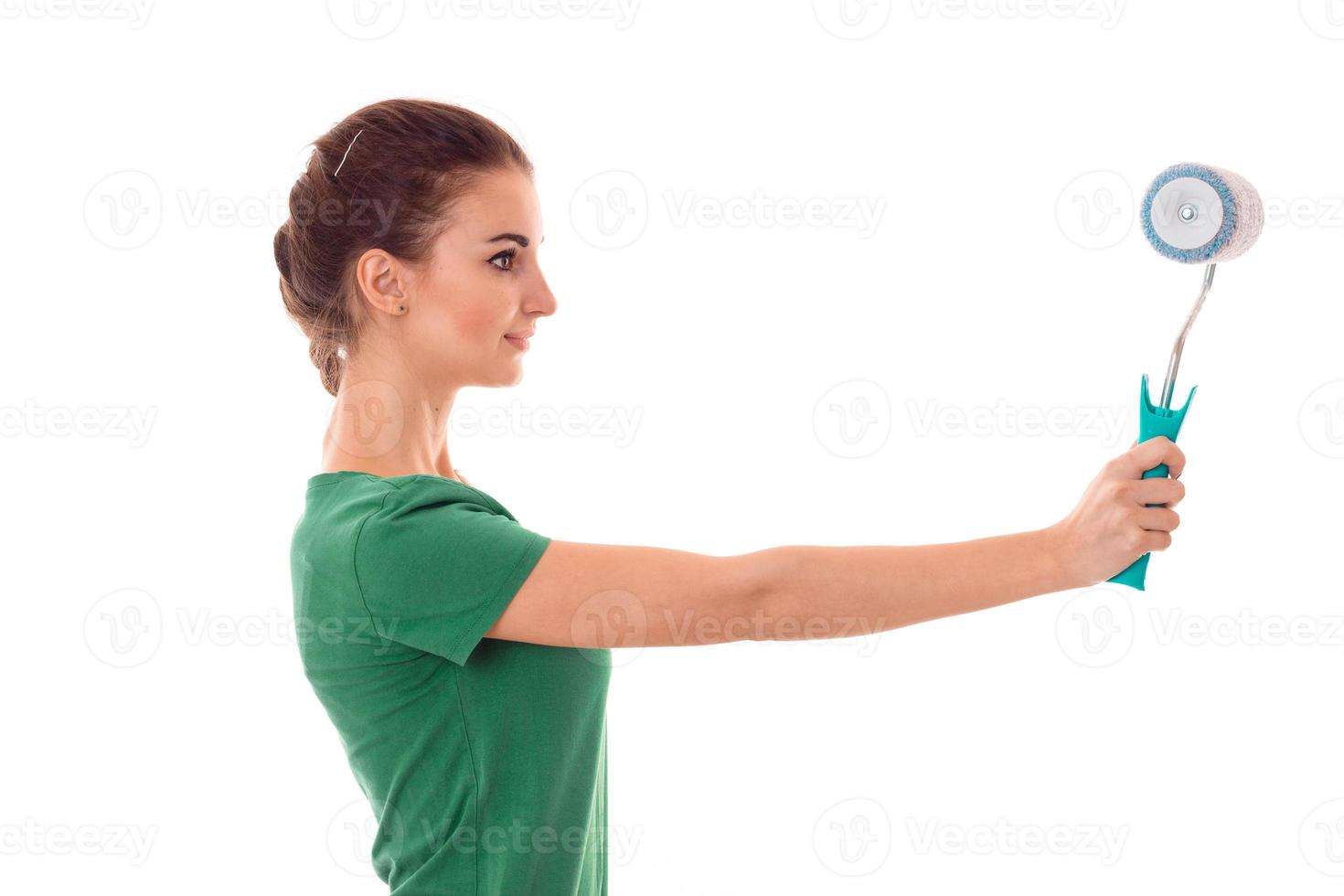 profeil of young pretty brunette woman builder in uniform with paint roller in hands make reovations isolated on white background photo
