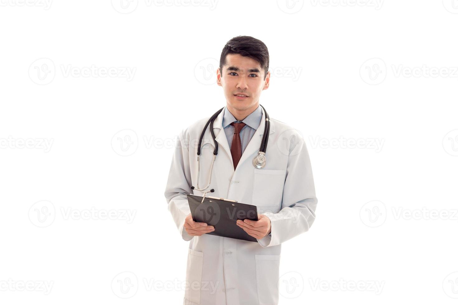 portrait of pretty young brunette male doctor in uniform with stethoscope posing isolated on white background photo