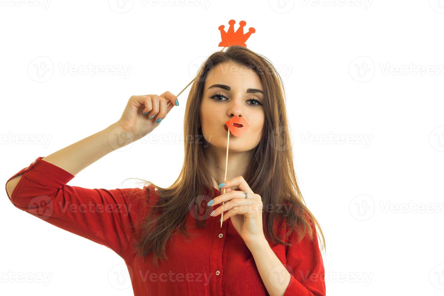 una joven increíble con una blusa roja se mantiene cerca de los maniquíes de papel de la cara para la foto