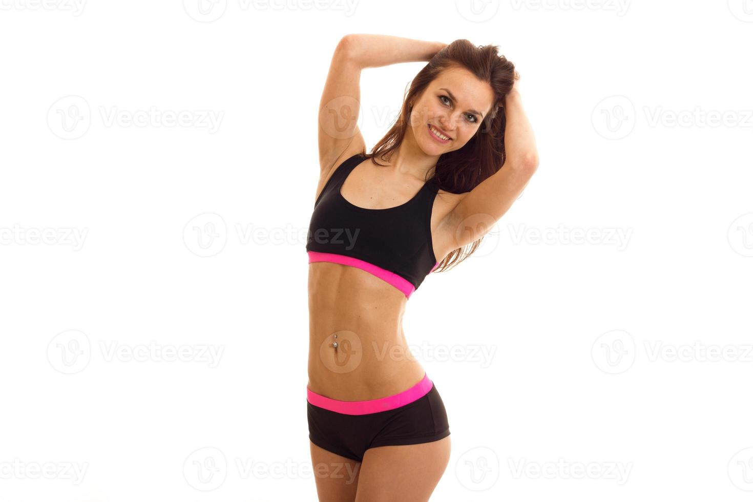 beautiful fitness girl sporting short shorts and top smiles and keeps hands near hair photo