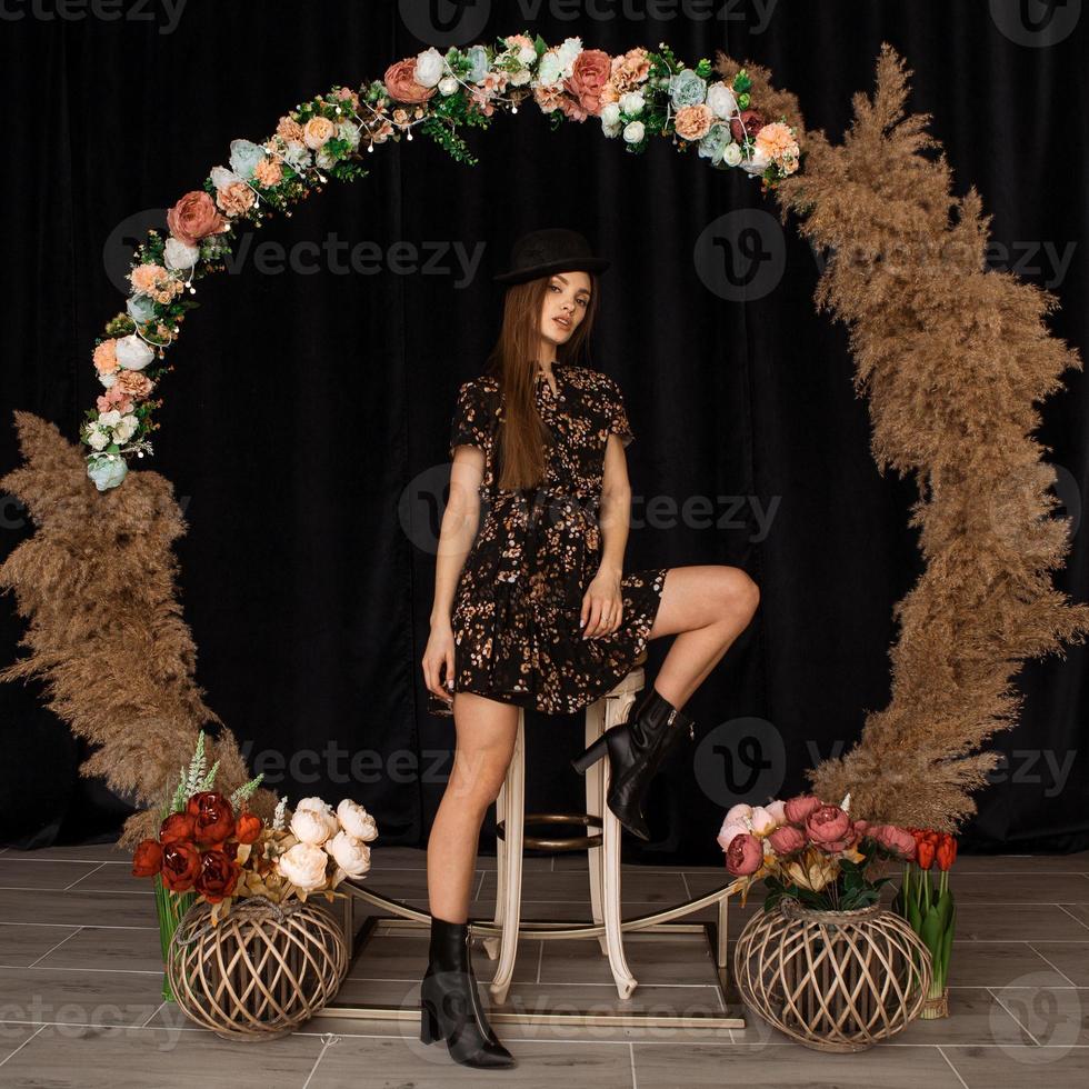 hermosa mujer posando en círculo de madera muerta en vestido con estampado de flores foto