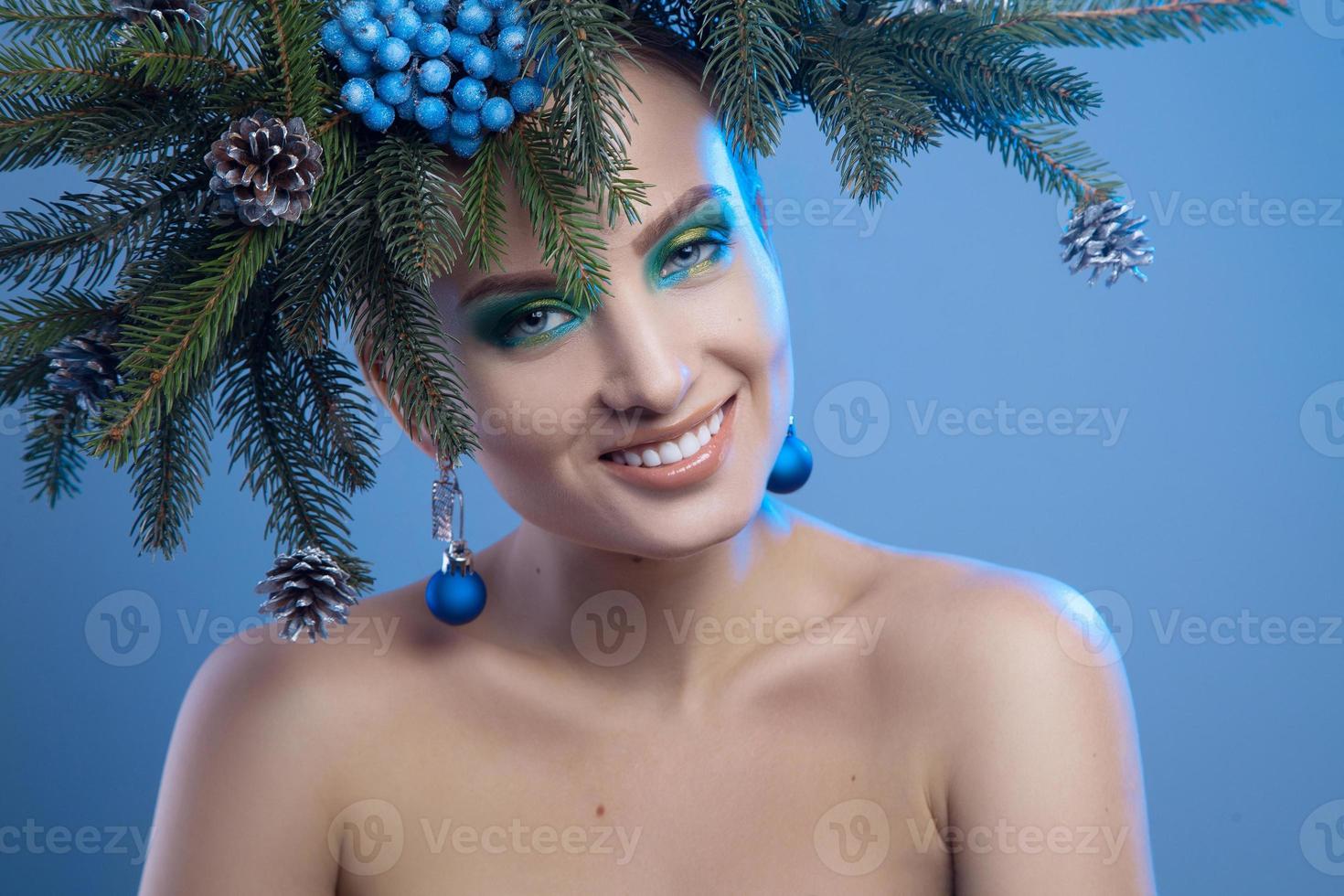 foto en primer plano de una joven belleza con corona de árbol de Navidad en la cabeza sonriendo a la cámara