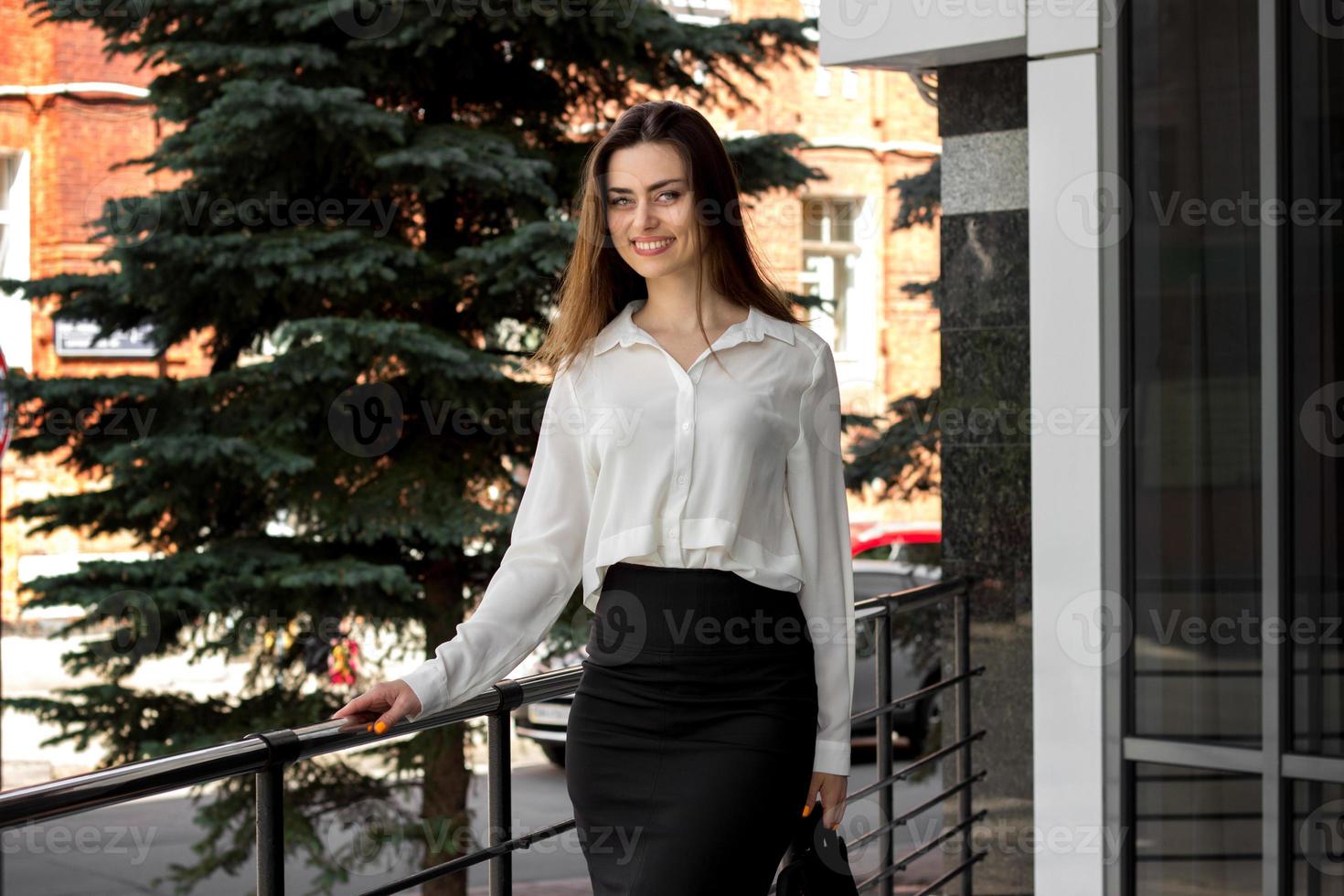 Cheerful young business girl smiles on camera photo