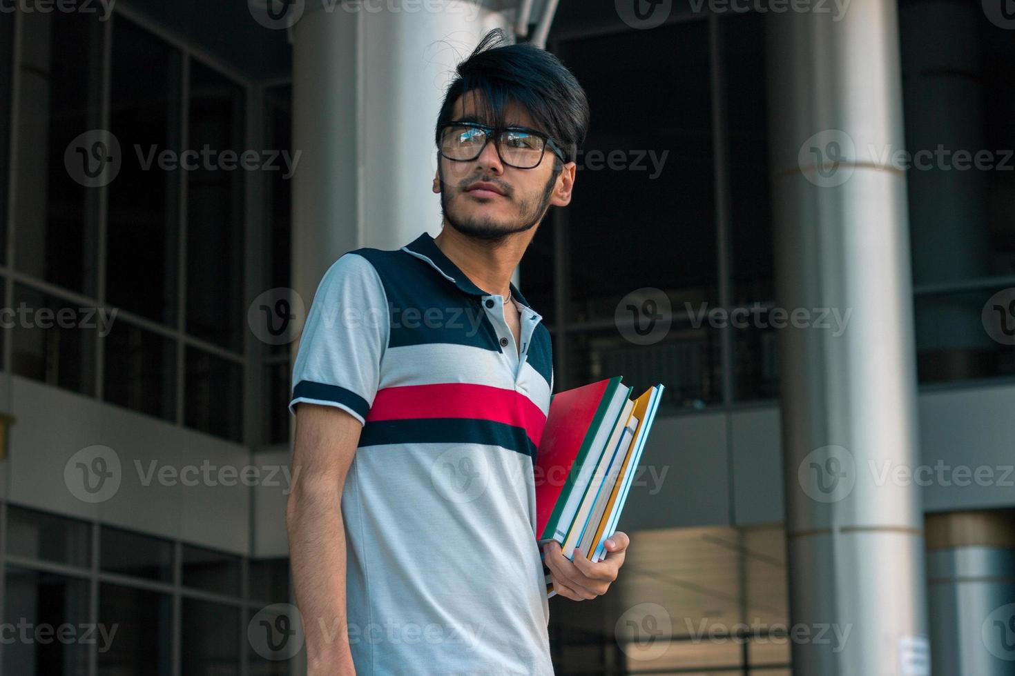 handsome young guy in glasses standing and holding a book photo
