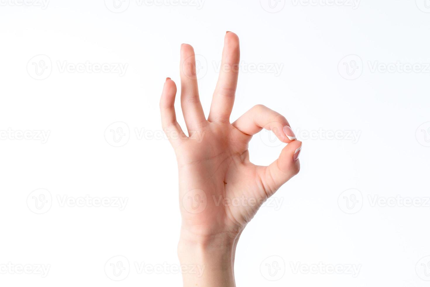 la mano femenina que muestra el gesto de ponerse en contacto con el dedo índice y el pulgar está aislada en un fondo blanco foto