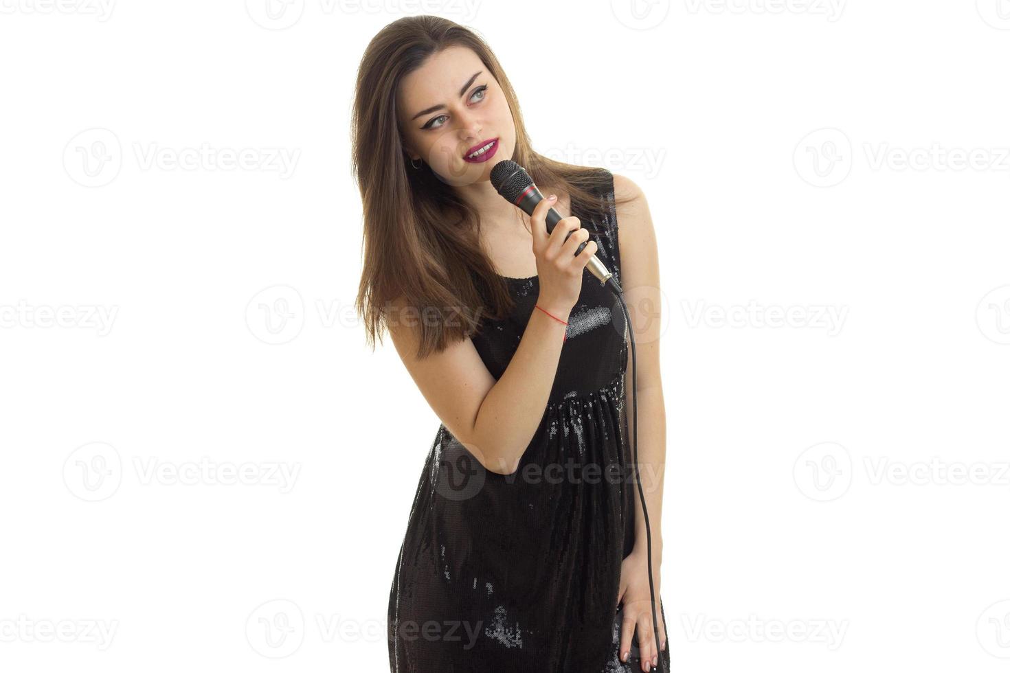 Cute young brunette in black dress singing karaoke photo