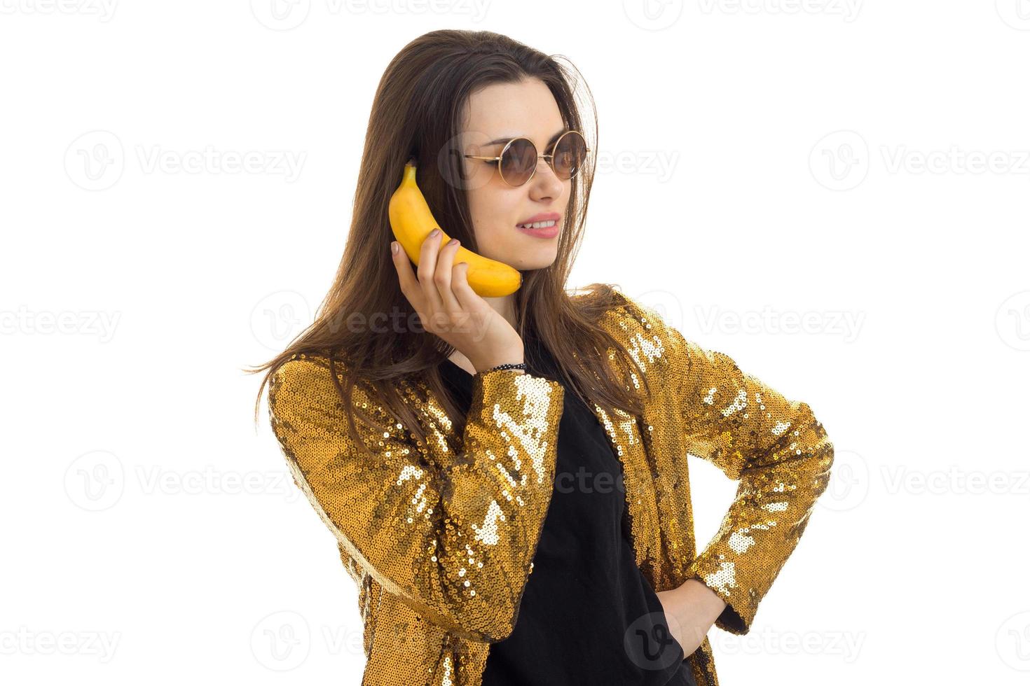 cheerful brunette woman in golden jacket holding a banana photo