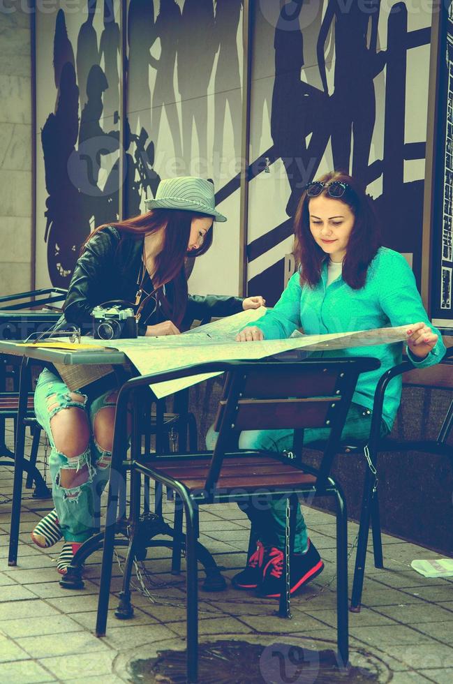 two women sitting at a table on the street photo