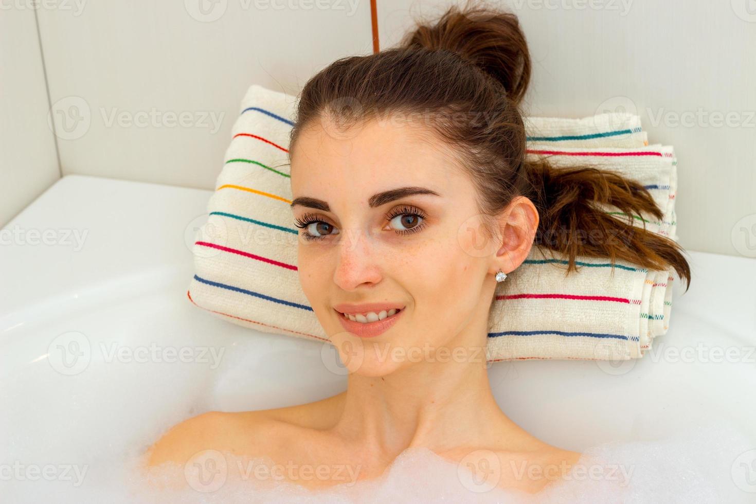 hermosa joven yace en un jacuzzi con espuma foto