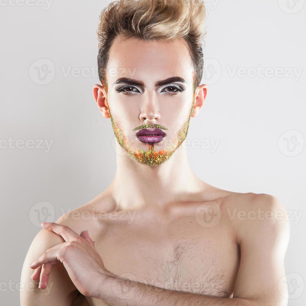 Attractive male model looking at camera with makeup and multicolor beard photo