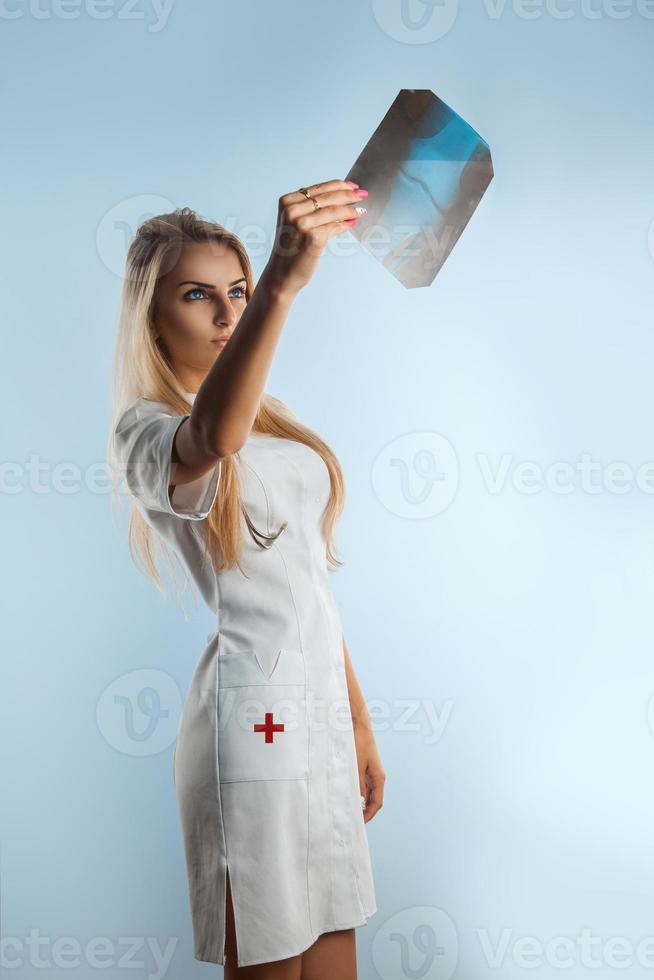 Photo of beautiful adult blonde nurse looking at x-ray photo