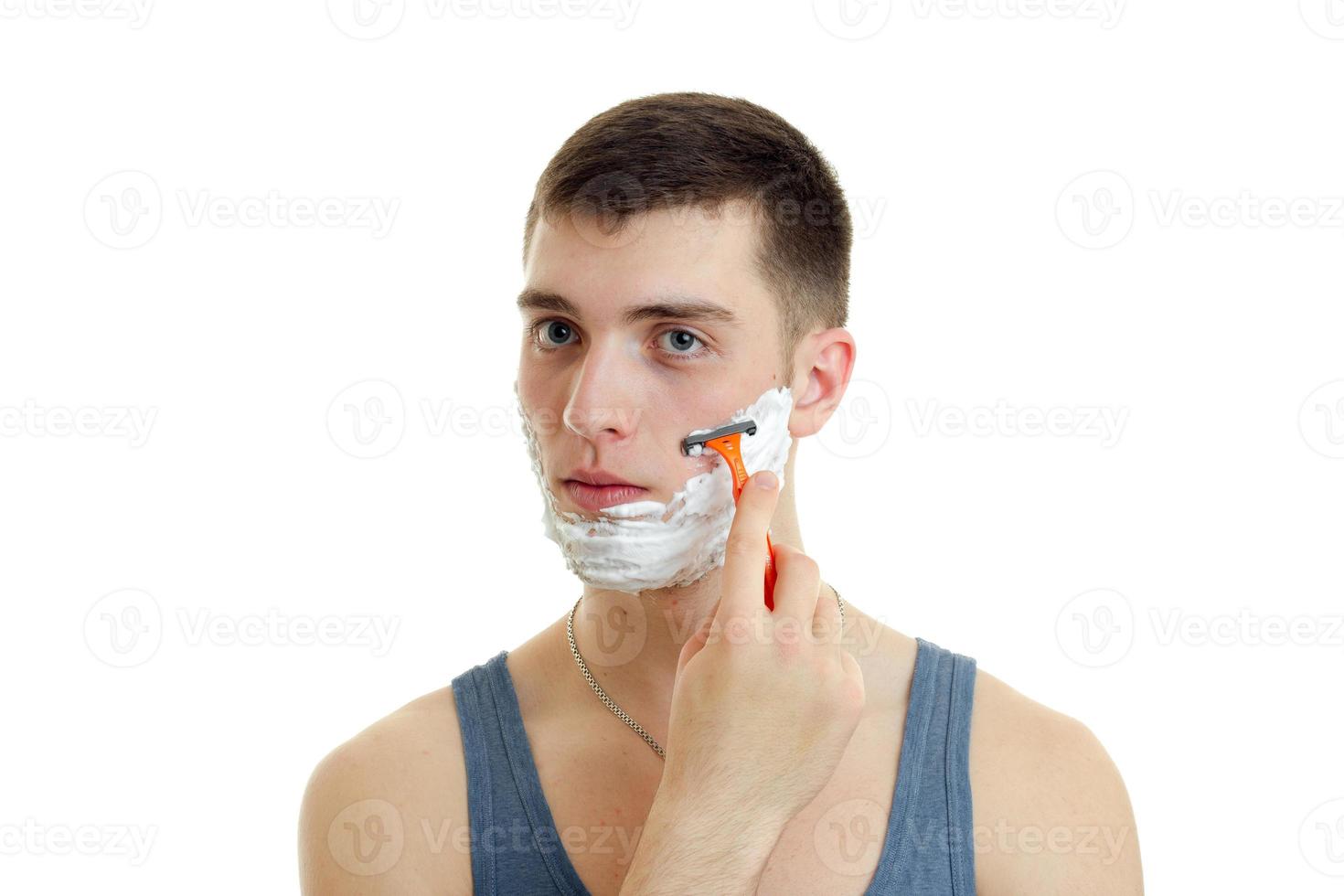 guy looks into the distance and shaves his beard with a foam photo
