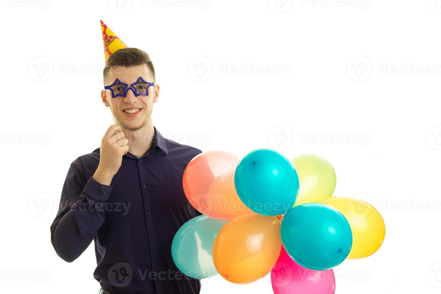 perky young guy keeps near eye paper glasses and lots of colored balls photo