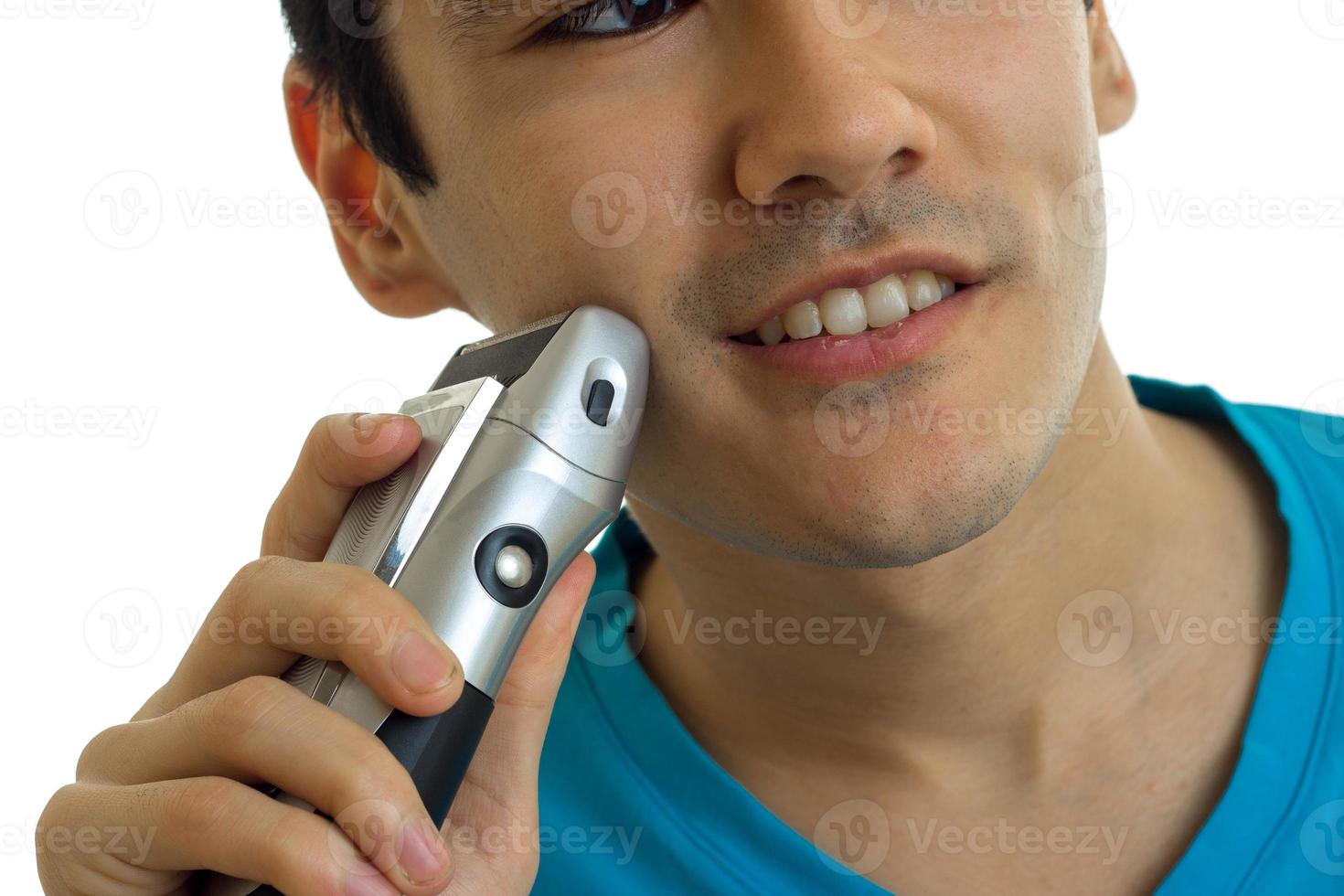 Portrait of a young handsome guy who smiles and shaves his beard close-up photo