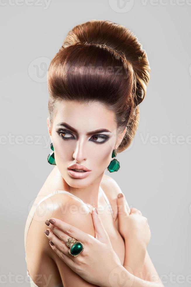 Portrait on grey background of young girl with creative hairstyle and nice accessories photo
