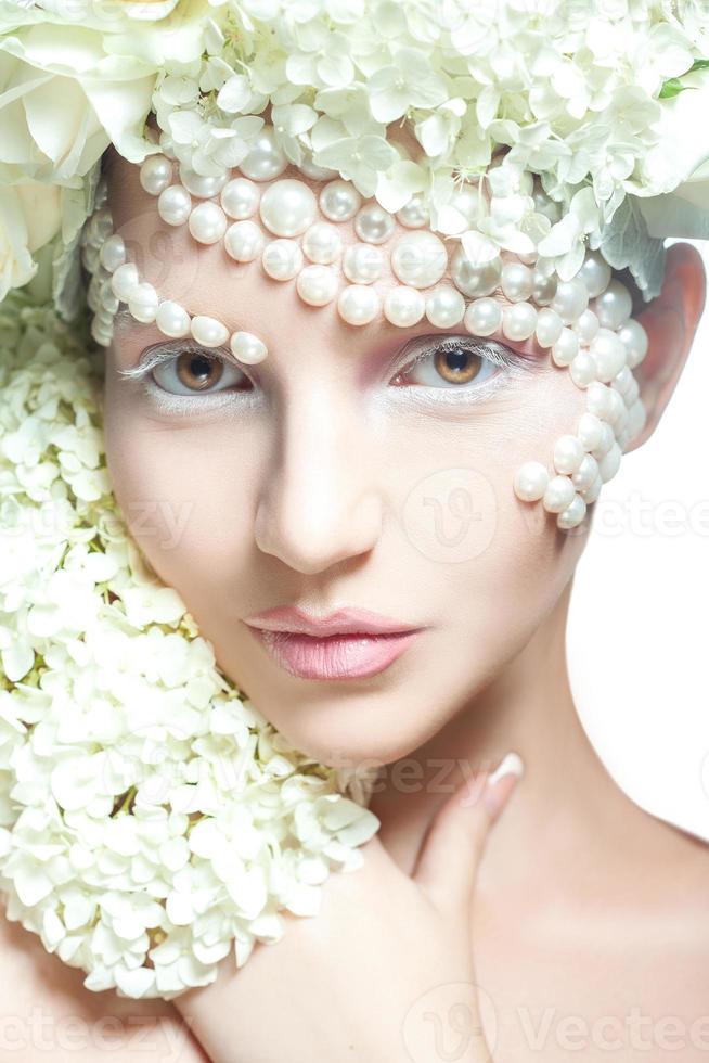 hermosa joven mirando a la cámara en el estudio. maquillaje tierno y accesorios creativos con flores. foto