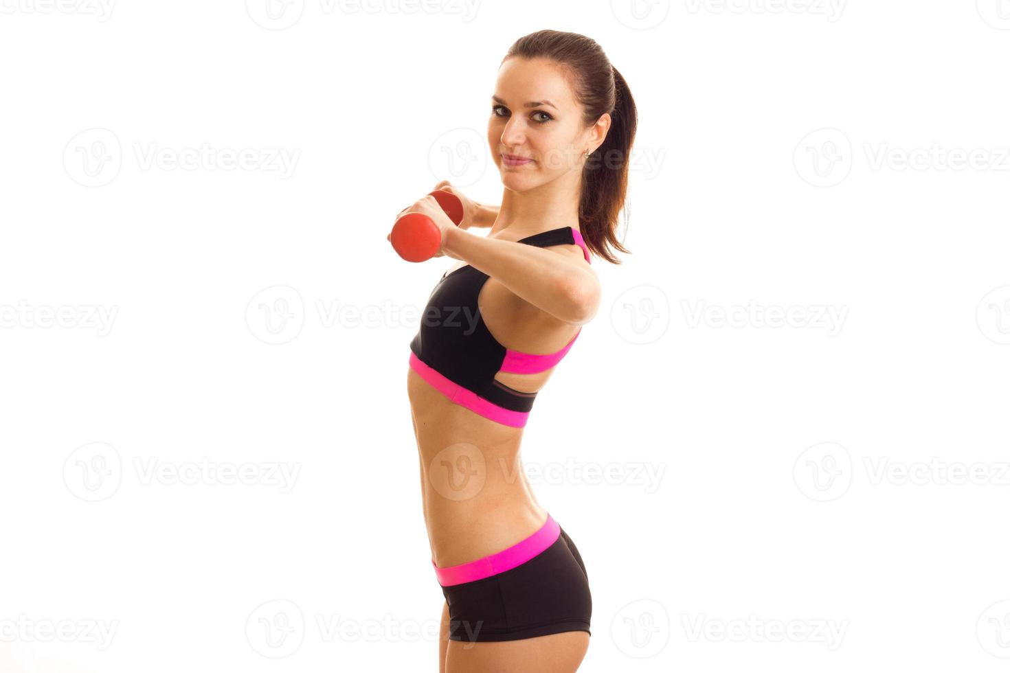 young slender sport girl stands sideways and holding a dumbbell photo