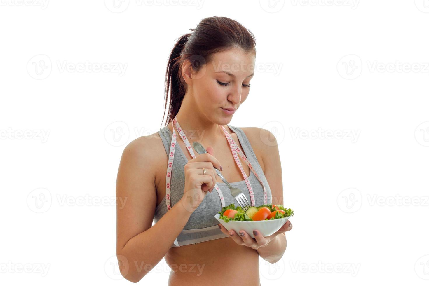 linda chica delgada en la parte superior sostiene un gran plato de ensalada de cerca foto