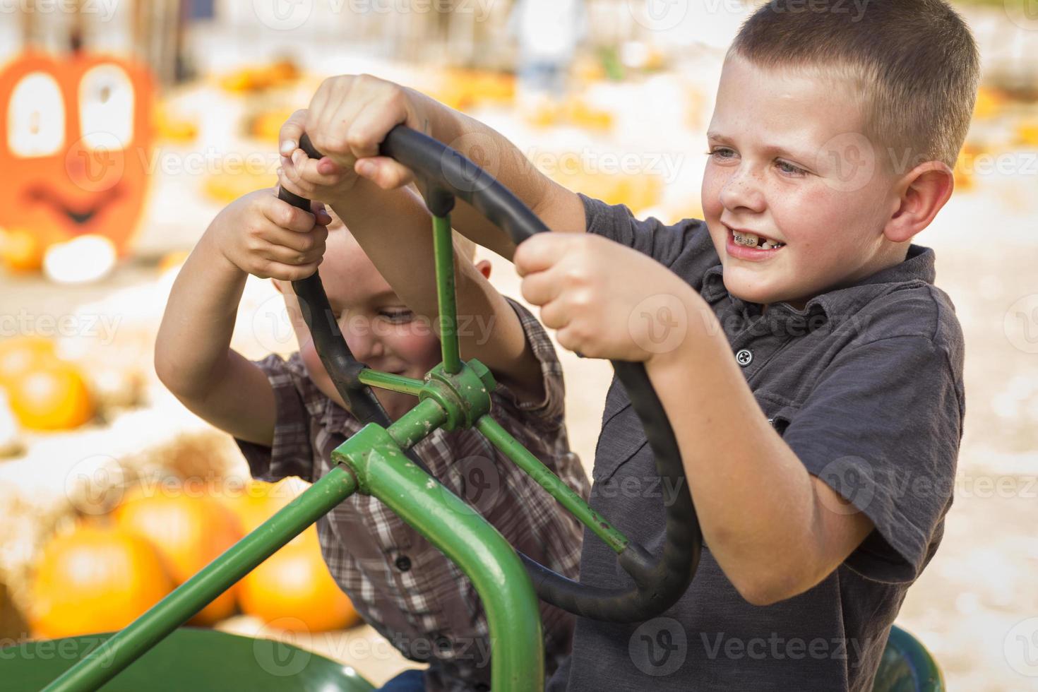 Adorable Young Boys Playing on an Old Tractor Outside photo