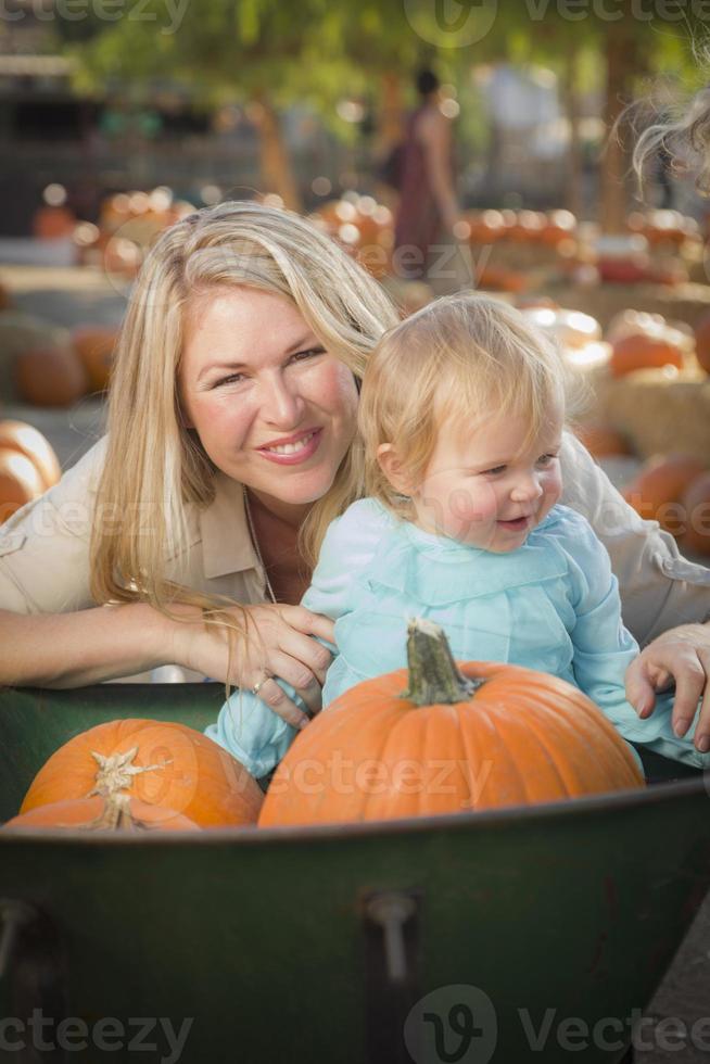 joven madre e hija disfrutan del huerto de calabazas foto