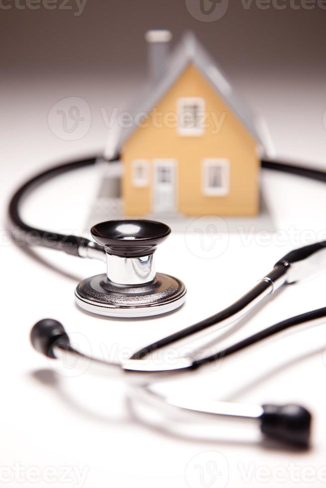 Stethoscope and Model House on Gradated Background photo