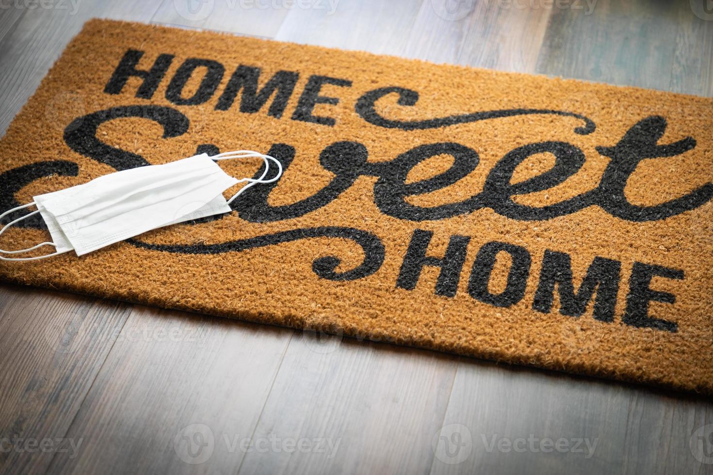 Medical Face Masks Rests on Home Sweet Home Welcome Mat Amidst The Coronavirus Pandemic photo