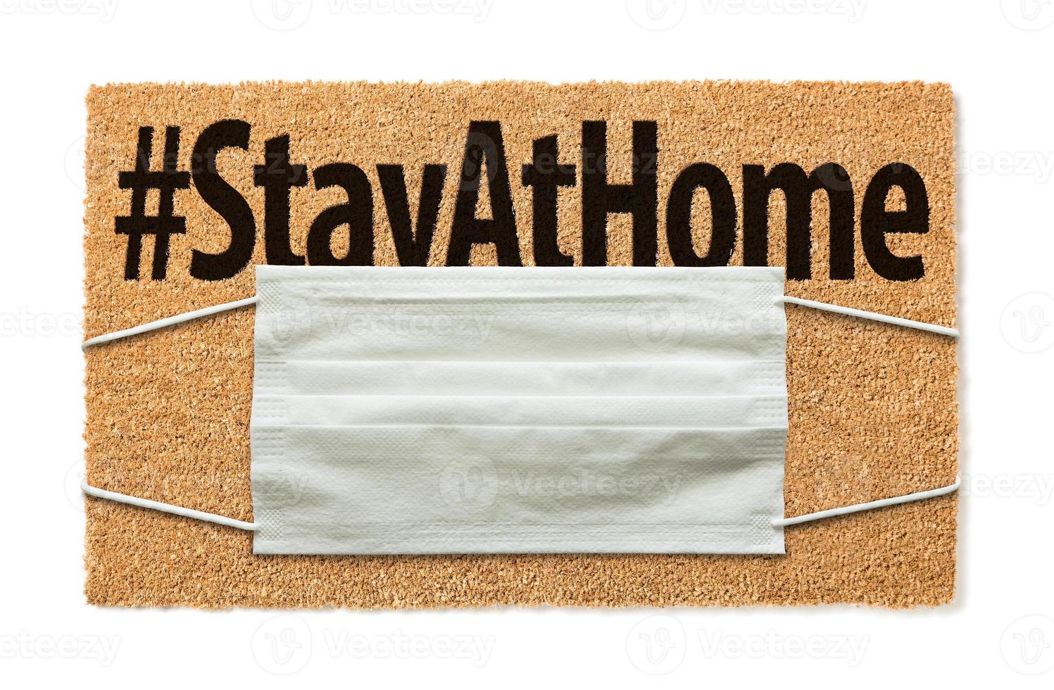 Welcome Mat With Medical Face Mask and Stay At Home Text Isolated on White Amidst The Coronavirus Pandemic photo