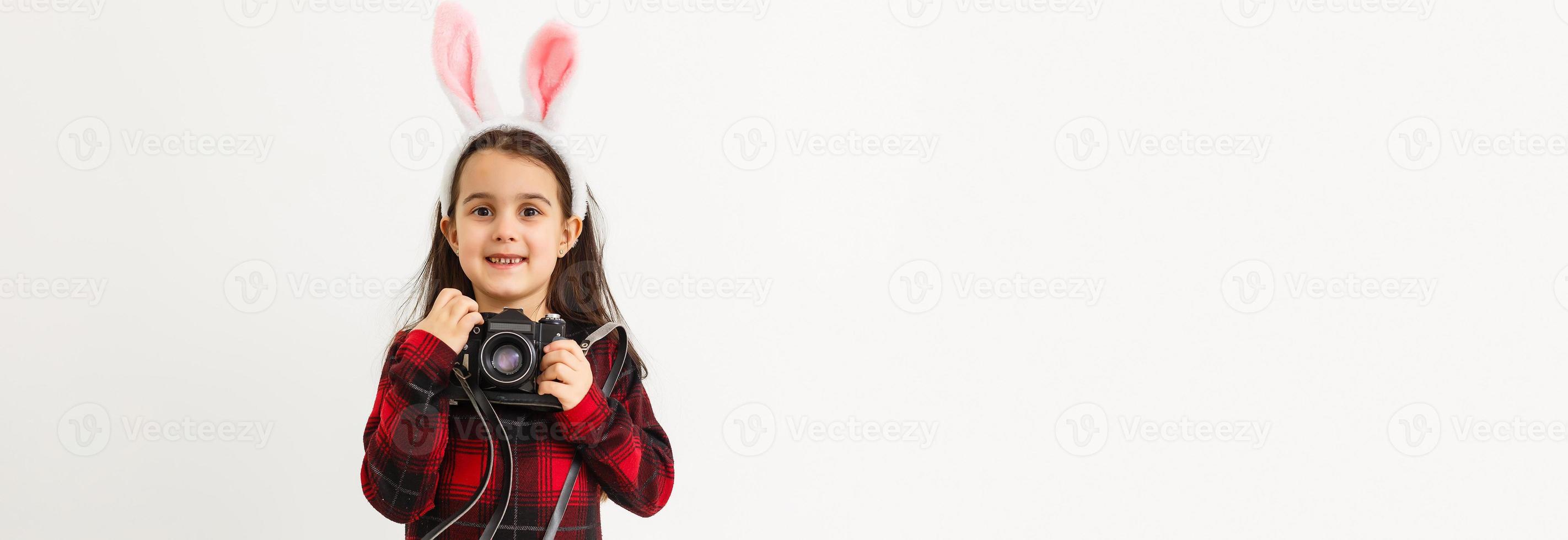 Surprised little girl wearing bunny ears, lying on light wooden floor on Easter Holiday. photo